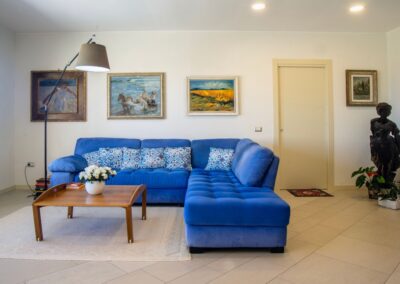 Soggiorno luminoso con divano blu in una casa vacanza